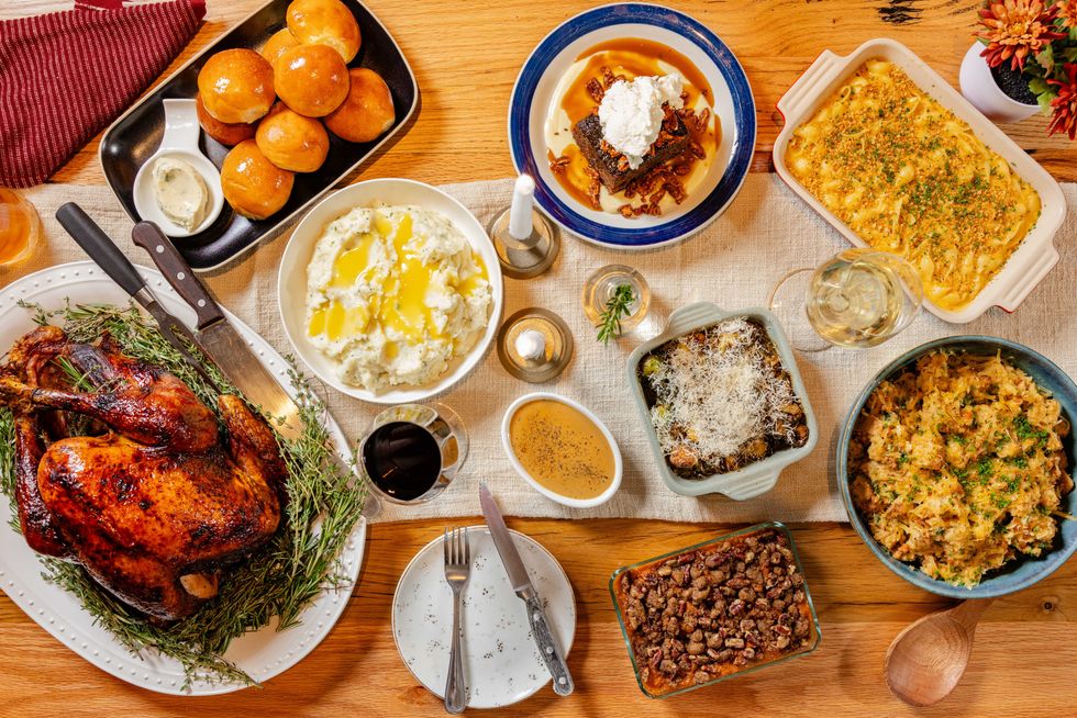 Picture of turkey and several sides, including mashed potatoes, green bean casserole, and rolls.