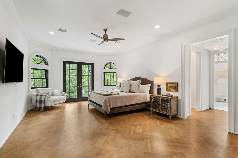 Primary suite bedroom of 23227 Brownwood Lane, with hardwood floors and French doors leading to a patio