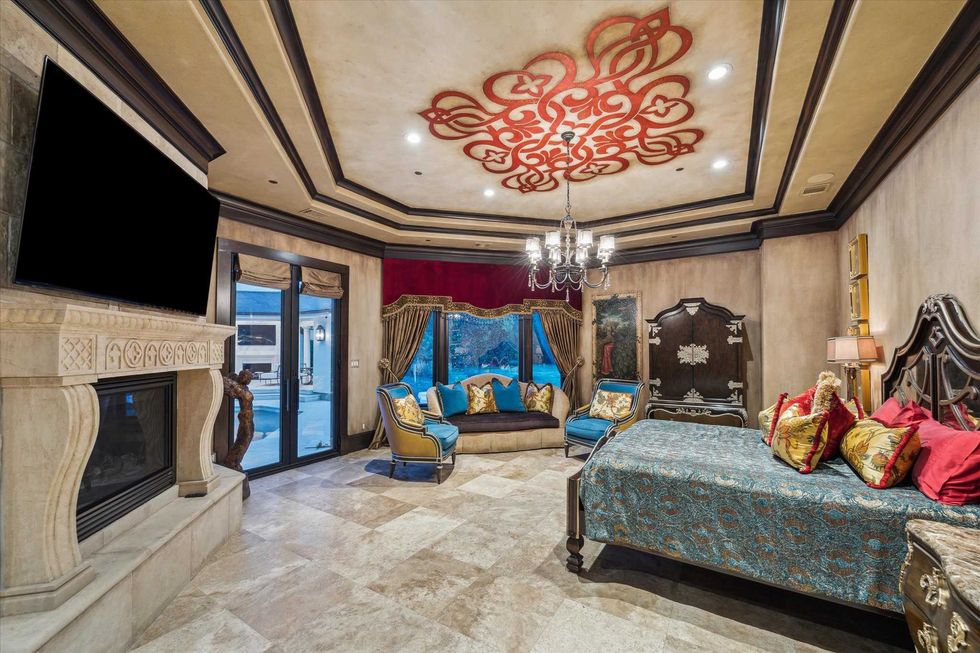 Primary suite of 11095 Memorial Drive, with a view of the pool outside, a massive fireplace and walnut floors