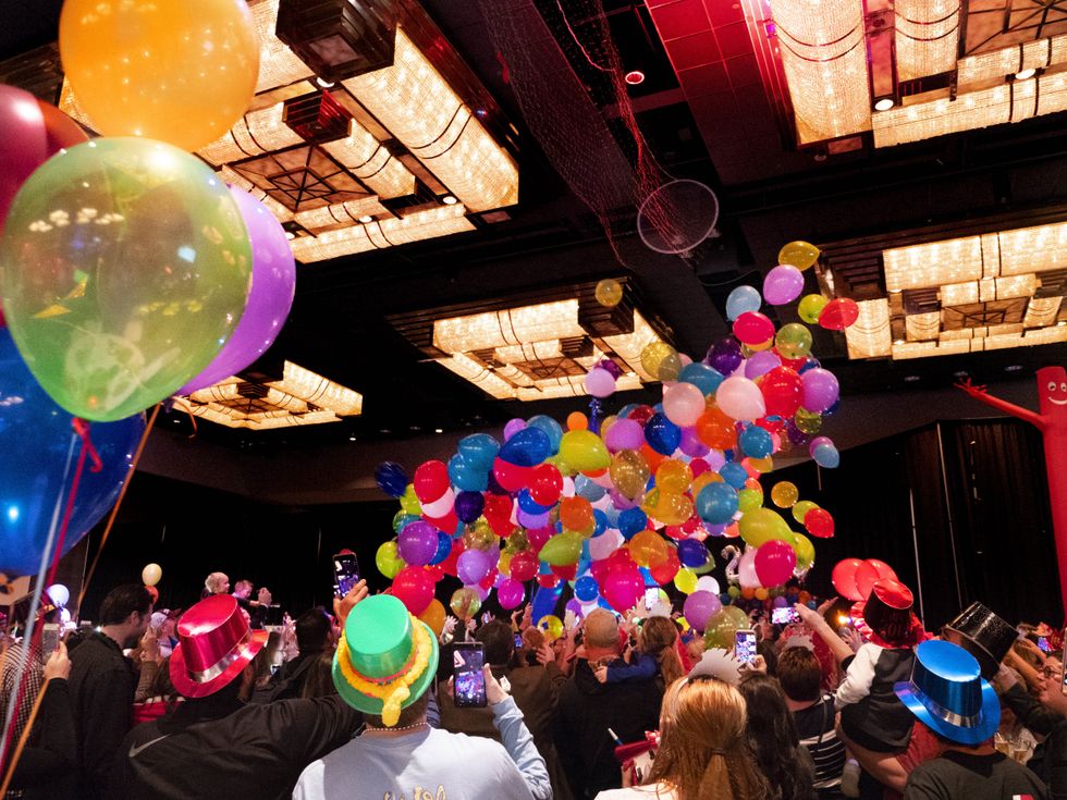 Revelers celebrating as balloons drop from the ceiling.