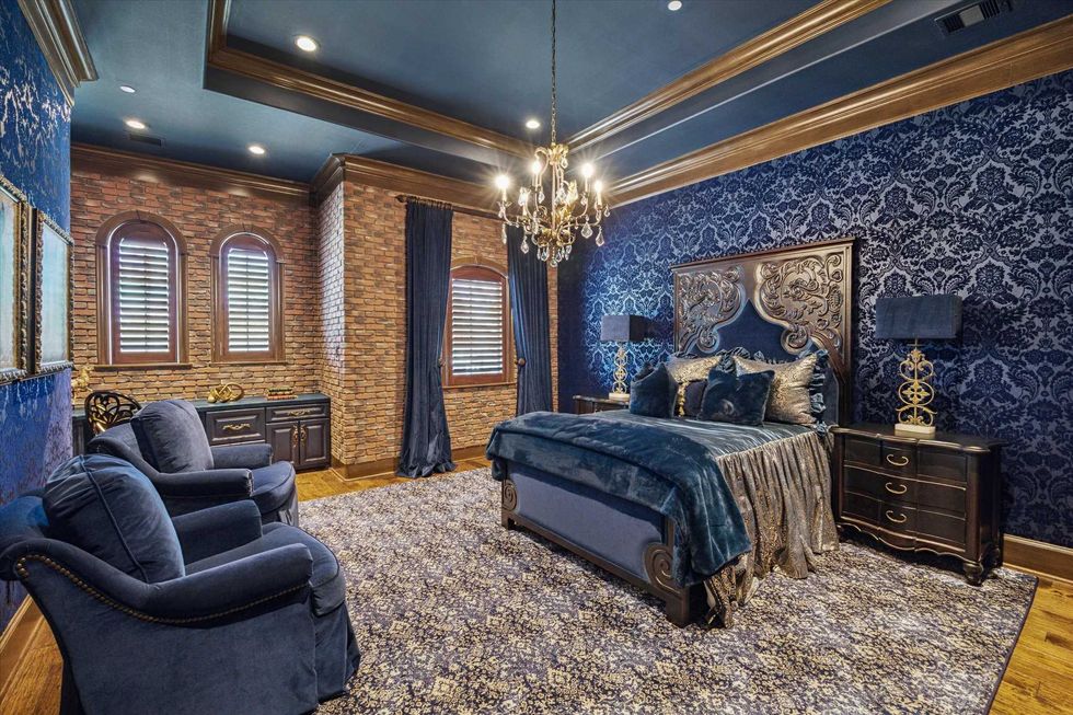 Secondary bedroom of 11095 Memorial Drive with blue velvet wallpaper a blue bedspread and blue chairs