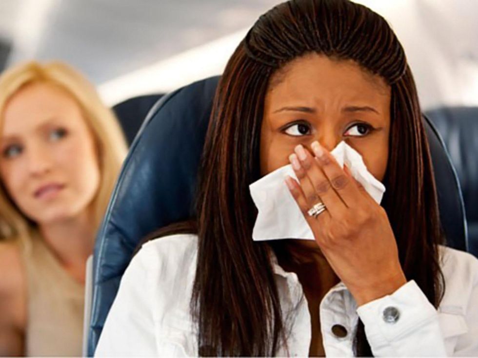 sick on airplane women holding tissue to nose