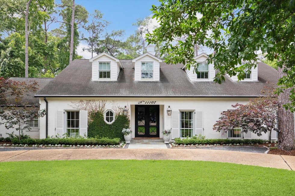 The front of 1107 Wickway, a white house with ivy growing on the left side of the double entry doors, and four gables at the top of the house.