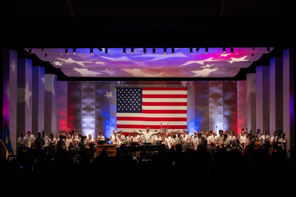 The Houston Symphony orchestra performing on stage with a giant American flag.