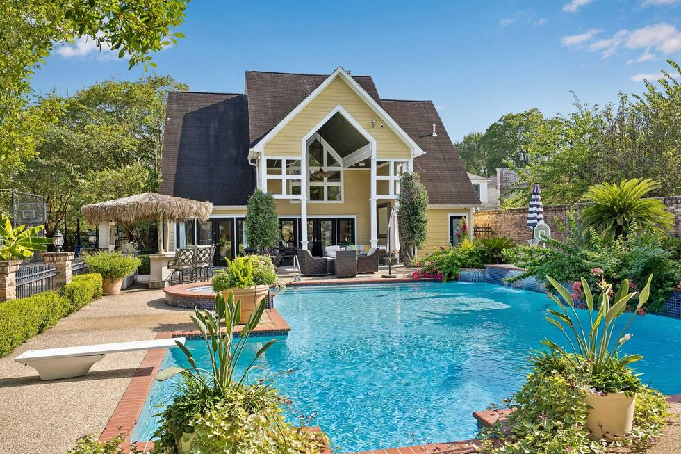 The pool house of 216 E. 26th St in the Heights, showing the house and a massive in-ground pool in the foreground