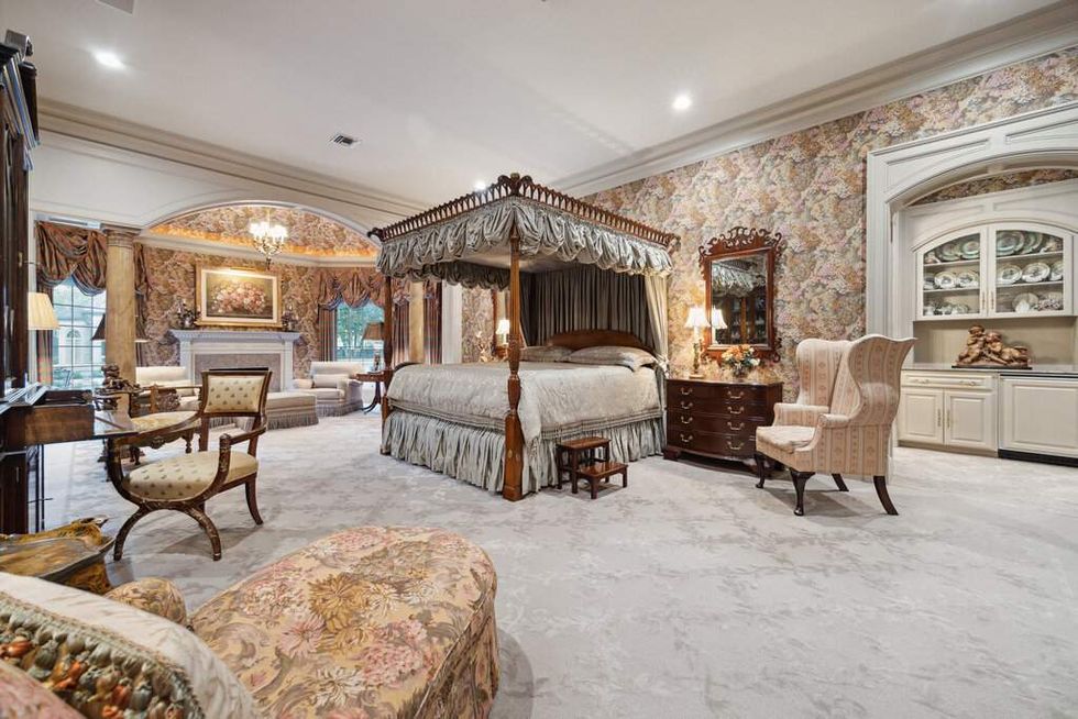 The primary suite of 412 Timberwilde Lane, showing a canopied bed, fireplace and seating