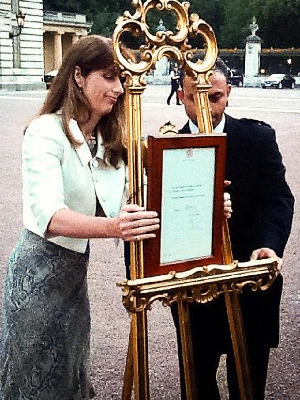 The Queen's Press Secretary and a footman post the official announcement of the birth of The Duke and Duchess of Cambridge's baby on an easel in Buckingham Palace forecourt