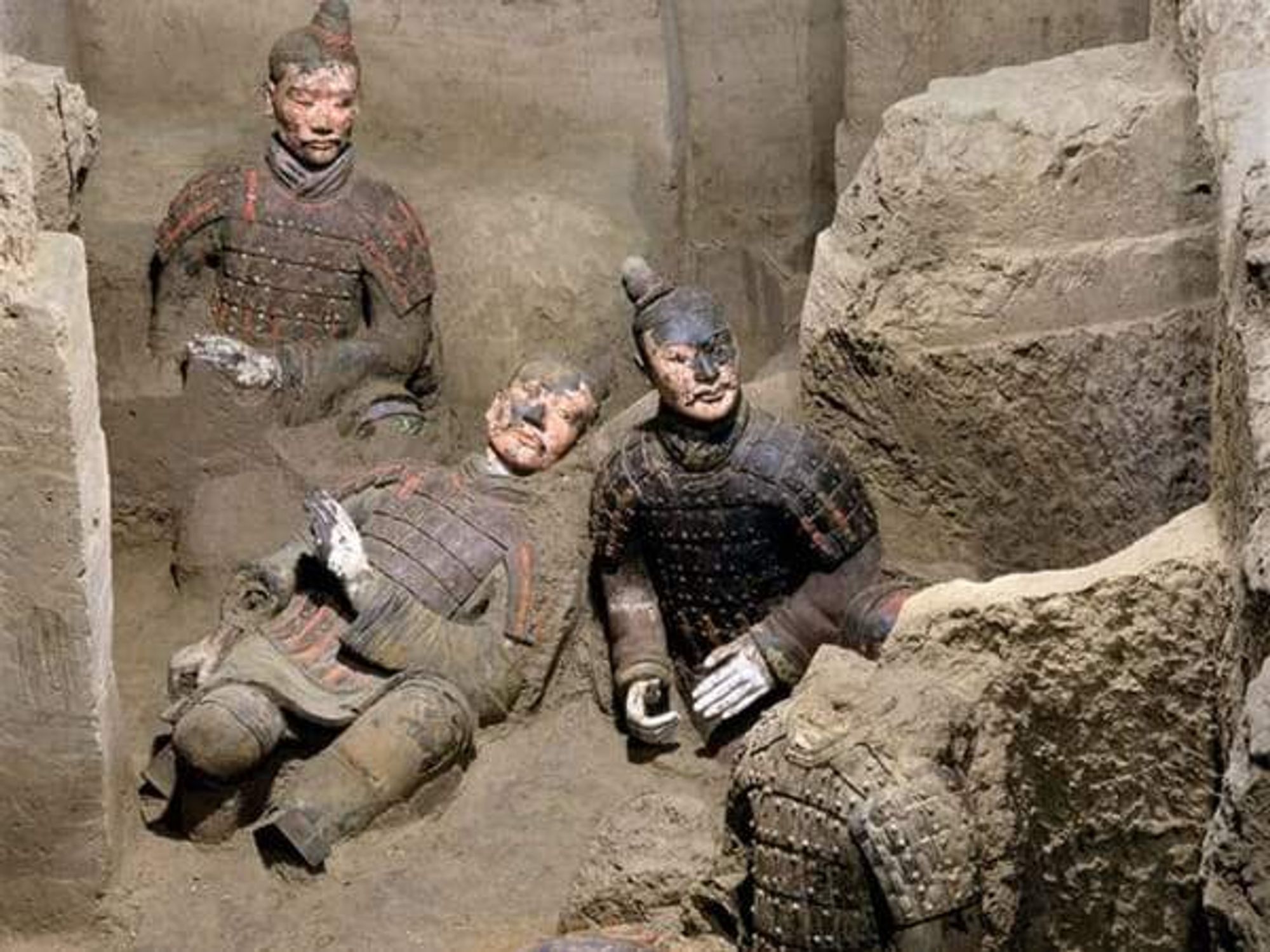 Three Chinese Terracotta Warriors amid an archeological dig.