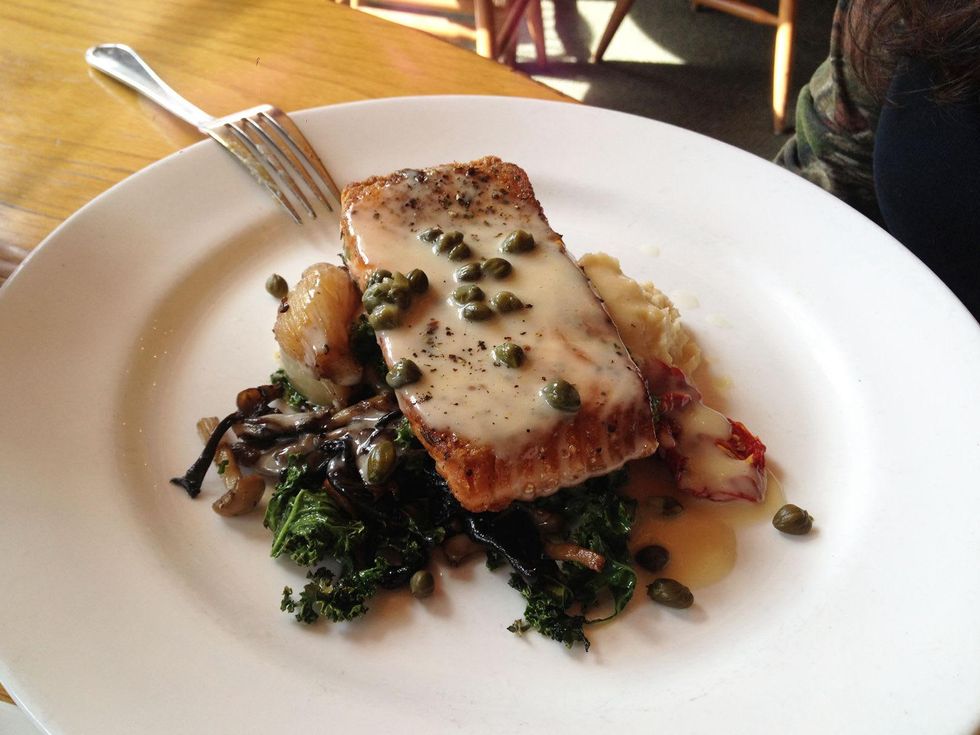 Trenza curried lemon caper sauce over pan-seared salmon with mushrooms and kale