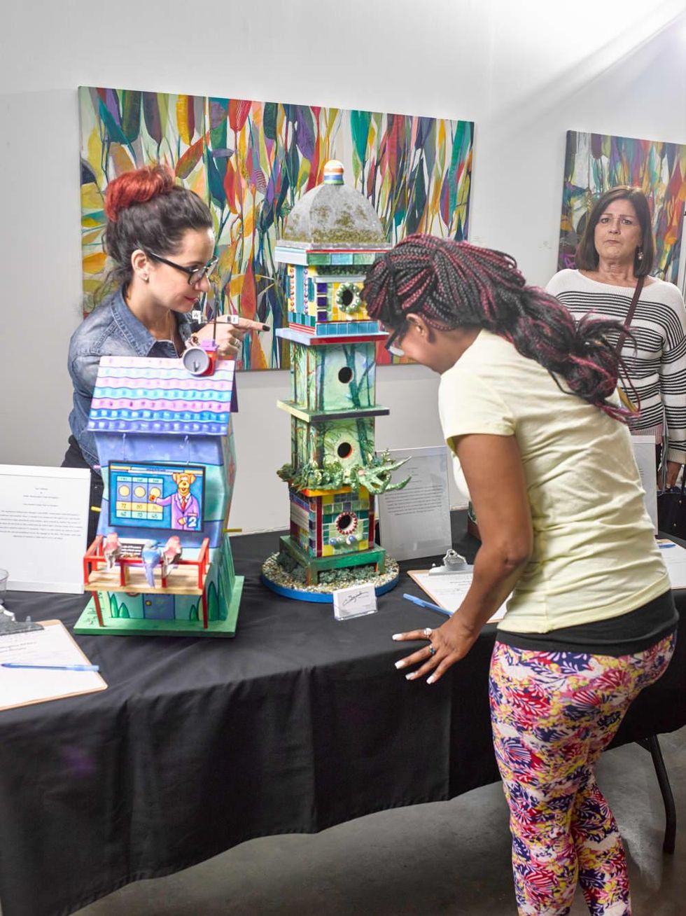 Trish Motolinia and Harralyne Landrove check out the celebrity birdhouse by Sharon Kopriva and Chris Silkwood at Sawyer Yards Artist Stroll