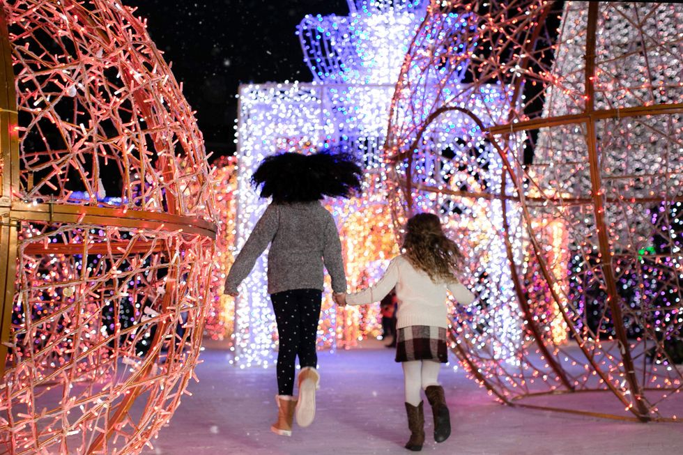 Two girls running through a light display at Classic Christmas