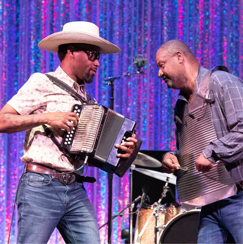 Two guys in jeans playing accordions.