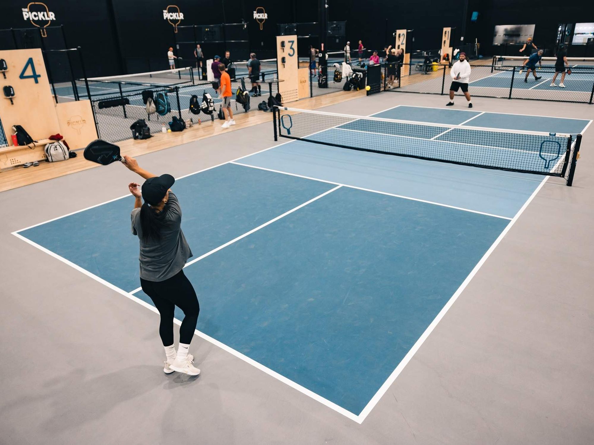 Two men play pickleball on a Picklr court.