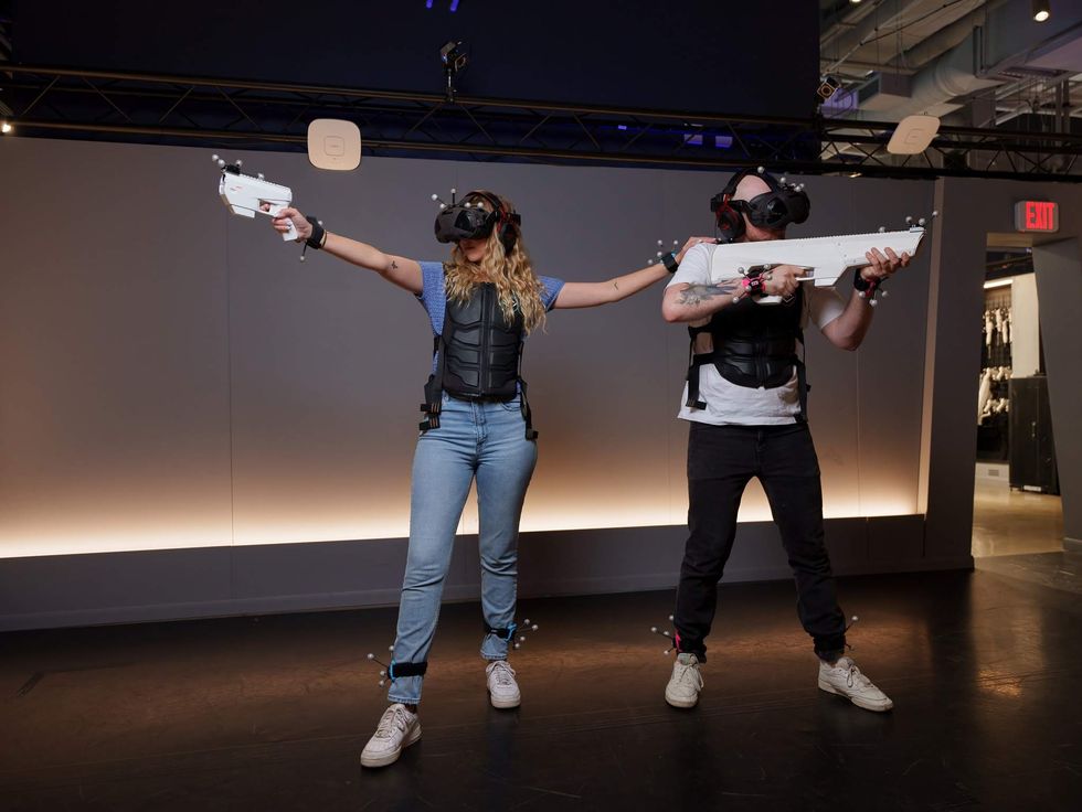 Two players in VR goggles with plastic guns.