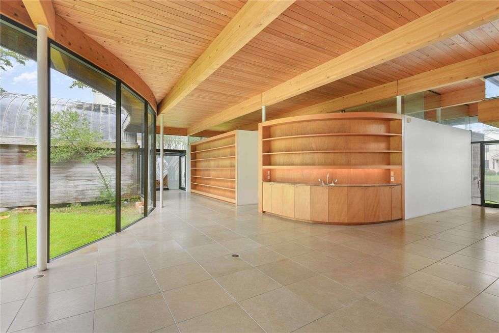 View of 701 Mulberry Lane's open living plan, with curing floor-to-ceiling windows on the left looking out to the yard