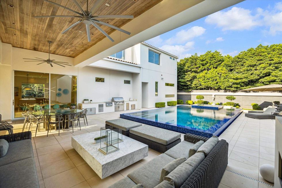 View of the backyard, outdoor kitchen, patio living room, and pool of 311 Brown Saddle St.