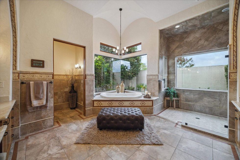 View of the primary suite bath of 21538 Mueschke Road with a deep soaking tub, walk-in shower and views of the grounds