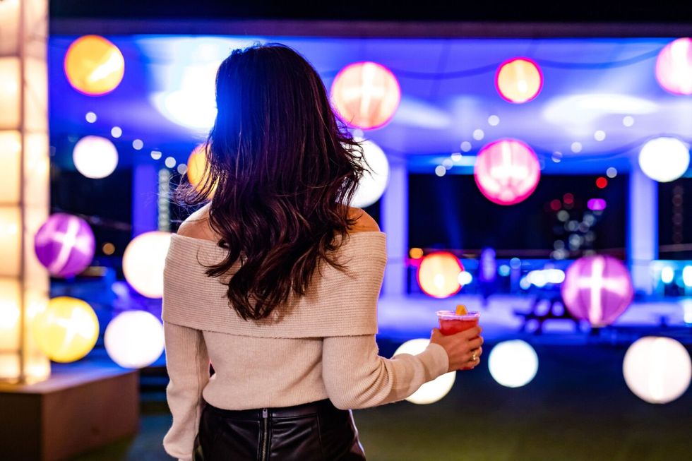 Woman holding a cocktail looking at lighted orbs